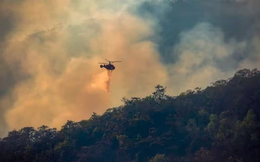 Helicopter dropping water retardant on a bushfire